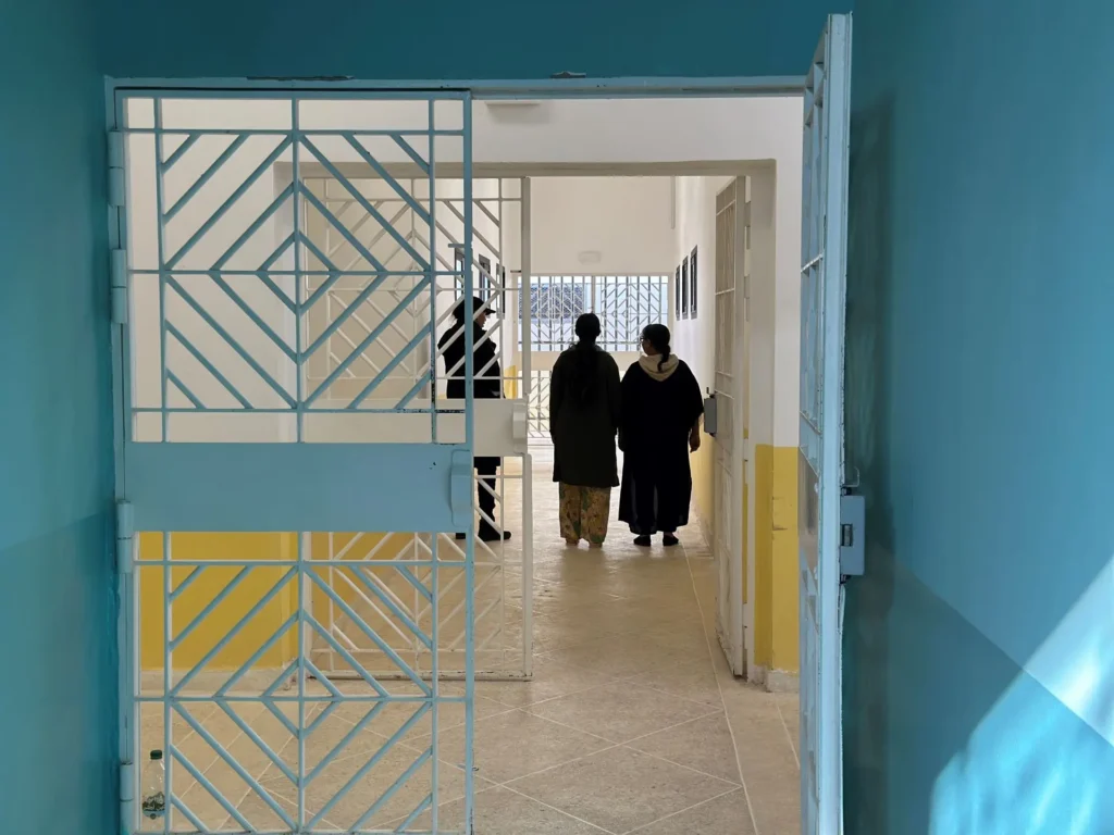 Two women seen from behind walking inside a prison
