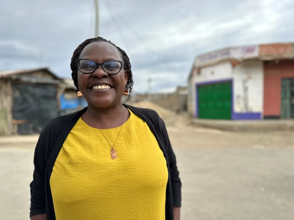 Millie Rono smiling in a yellow t-shirt and black cardigan