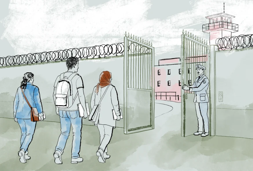Three people walking inside the gates to a prison