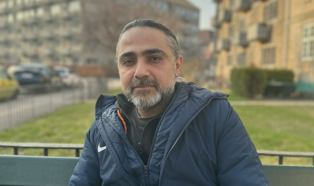 Portræt af Mustafa der står foran et boligområde