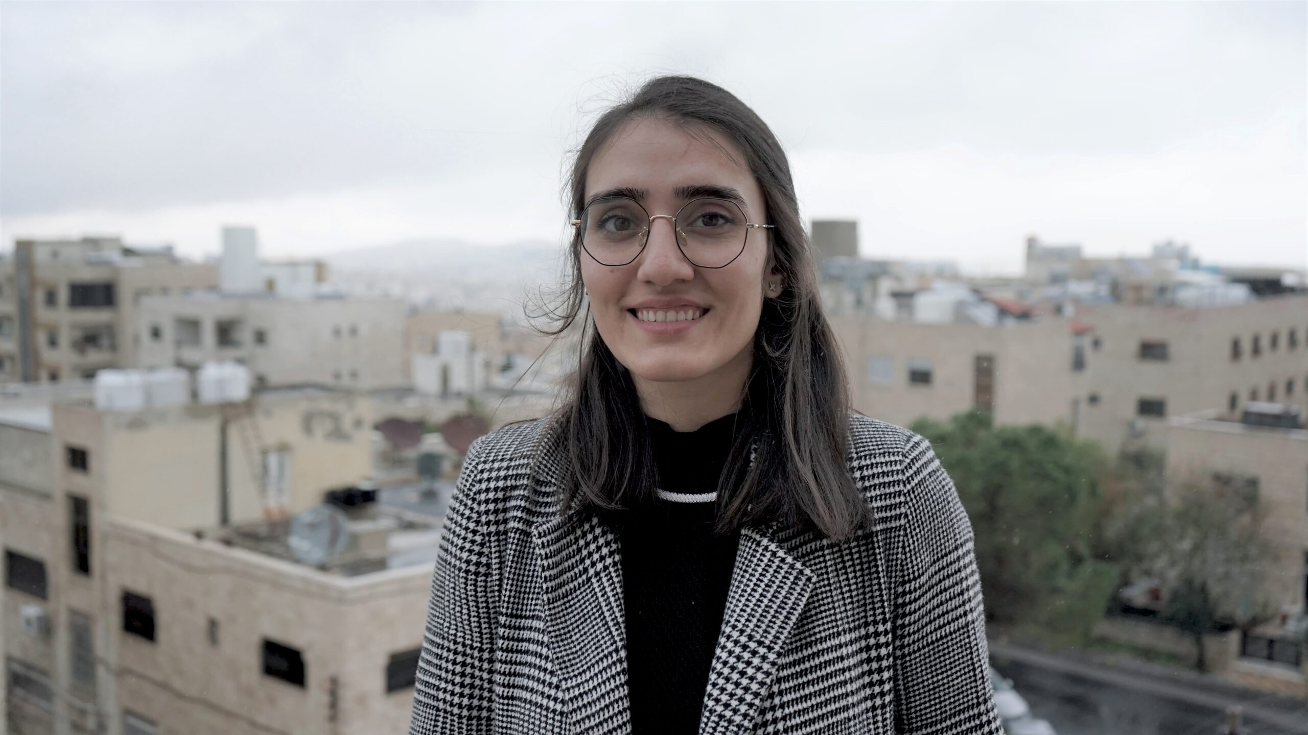 Fathia Zorba foran slørrede bygninger og himmel i Jordan